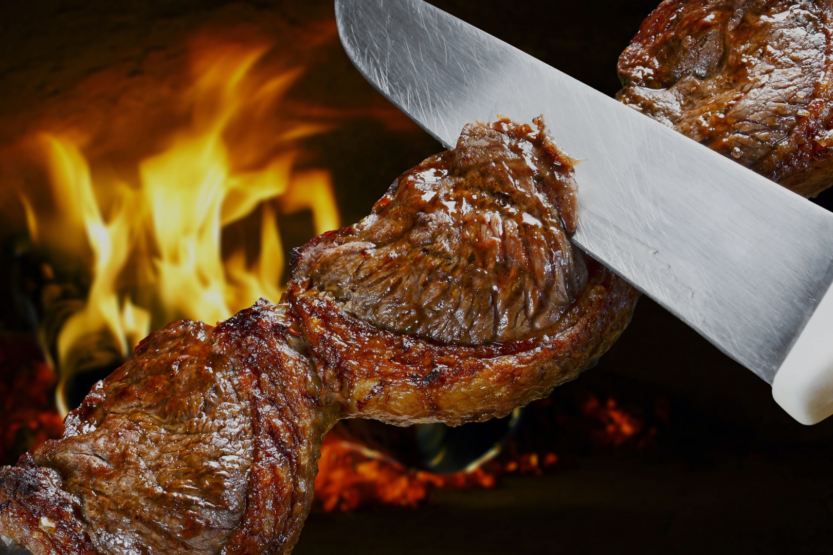 Carne bovina no espeto sendo fatiada